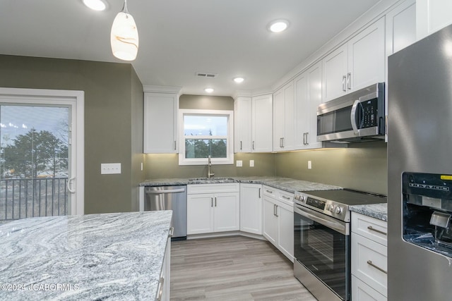 kitchen with pendant lighting, sink, light stone counters, white cabinetry, and stainless steel appliances