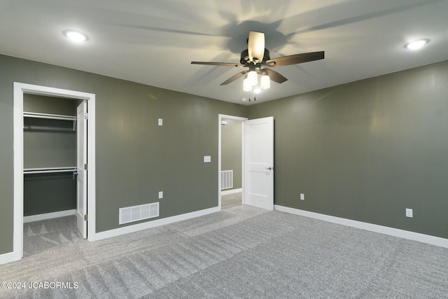 unfurnished bedroom featuring ceiling fan, a closet, light colored carpet, and a spacious closet