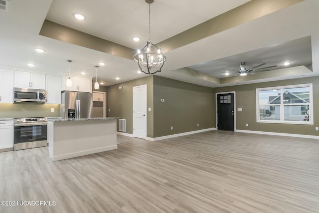 kitchen featuring decorative light fixtures, white cabinetry, appliances with stainless steel finishes, and a tray ceiling