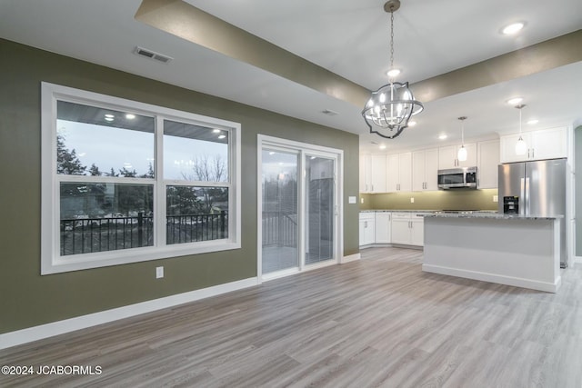 kitchen with light wood-type flooring, stainless steel appliances, pendant lighting, a notable chandelier, and white cabinets