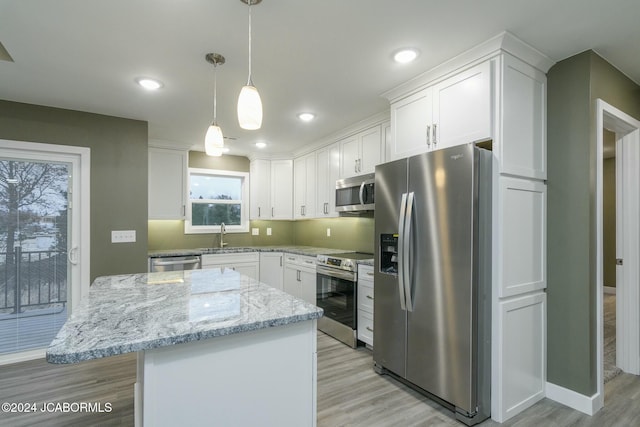 kitchen featuring pendant lighting, stainless steel appliances, white cabinetry, and light hardwood / wood-style floors