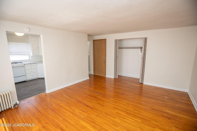210 E Dunklin St, Jefferson City, MO 65101 - unfurnished bedroom featuring radiator heating unit, light wood-style floors, baseboards, and connected bathroom