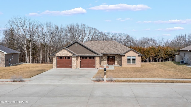 view of front of property with driveway, a front lawn, central AC, roof with shingles, and a garage