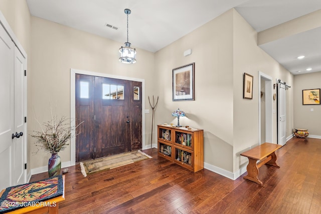 entryway with baseboards, visible vents, an inviting chandelier, hardwood / wood-style flooring, and a barn door