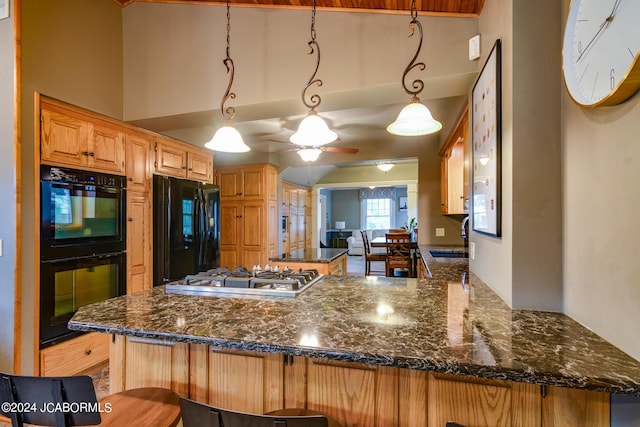 kitchen with sink, kitchen peninsula, black appliances, hanging light fixtures, and a breakfast bar