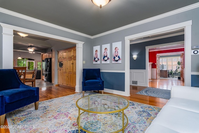 living room featuring hardwood / wood-style floors, ceiling fan, and ornamental molding