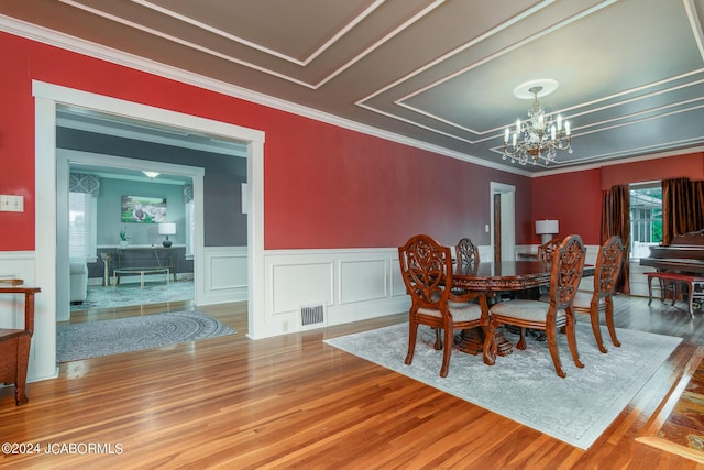 dining space with ornamental molding, hardwood / wood-style floors, and a notable chandelier