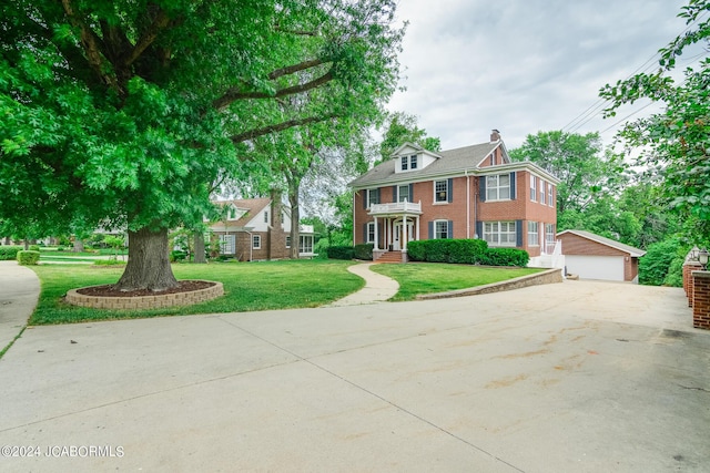 colonial-style house featuring a front yard, a garage, and an outdoor structure