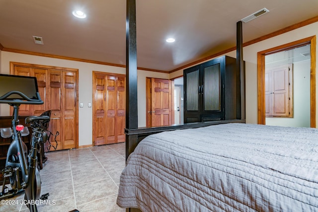 bedroom with crown molding, light tile patterned floors, and multiple closets