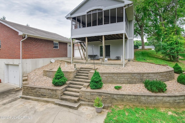 rear view of property featuring a patio, a sunroom, and a garage