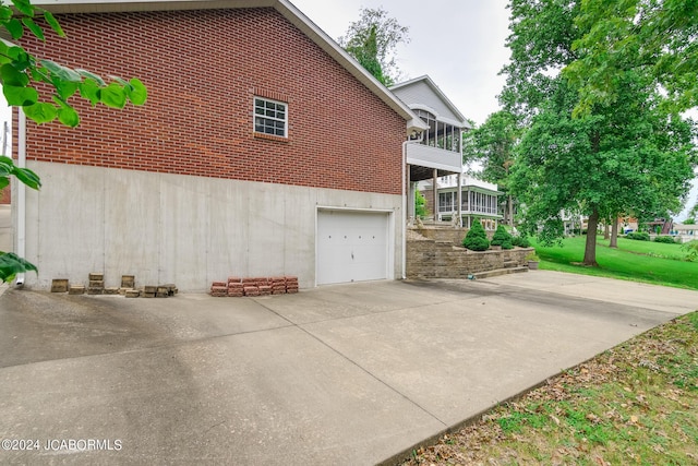 view of side of property featuring a sunroom, a balcony, and a garage