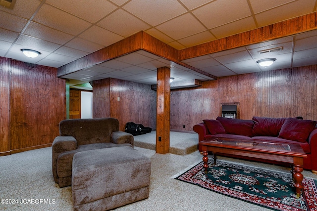 living room with a paneled ceiling, wooden walls, and carpet floors