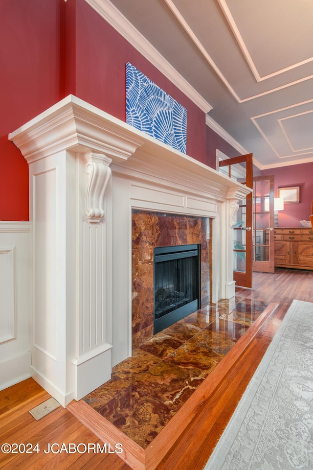 interior details with a tile fireplace, hardwood / wood-style flooring, and crown molding