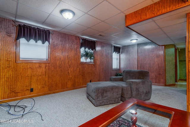 living area featuring wooden walls, carpet, and a drop ceiling