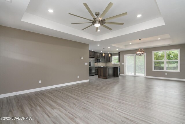209 Gavin Ln, Linn, MO 65051 - unfurnished living room with a raised ceiling, light wood-style flooring, ceiling fan, recessed lighting, and a chandelier