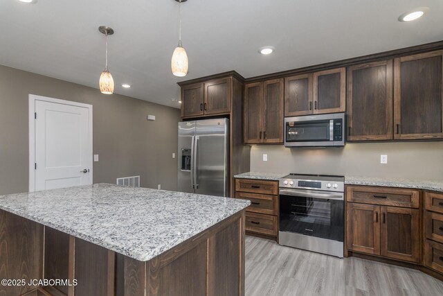 209 Gavin Ln, Linn, MO 65051 - kitchen with appliances with stainless steel finishes, light wood-type flooring, hanging light fixtures, dark brown cabinets, and light stone countertops