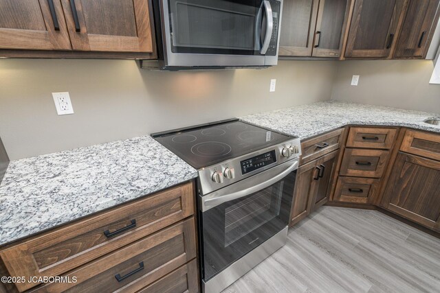 209 Gavin Ln, Linn, MO 65051 - kitchen featuring stainless steel appliances, light wood-style flooring, light stone countertops, and dark brown cabinetry