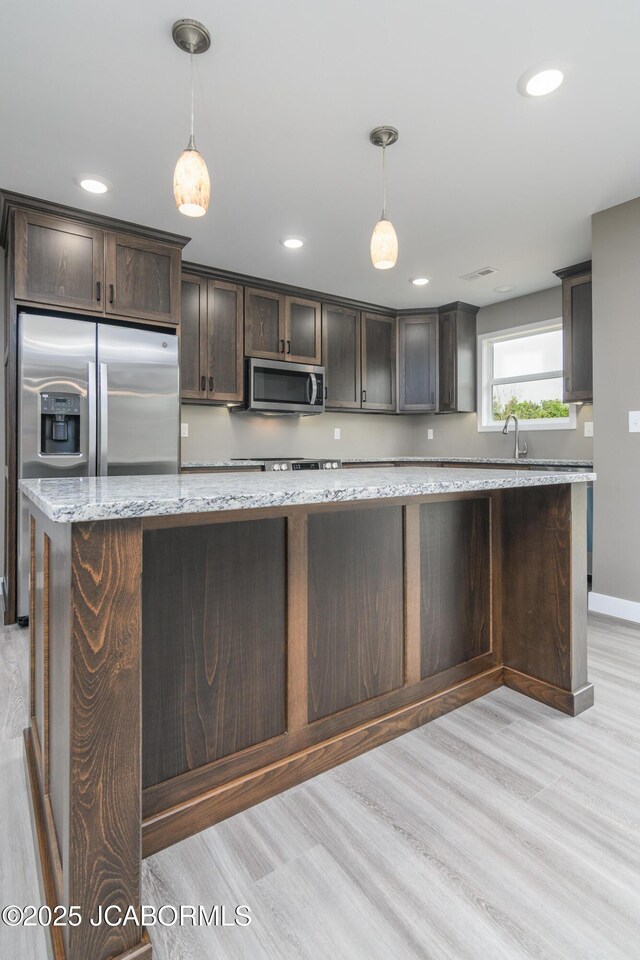 209 Gavin Ln, Linn, MO 65051 - kitchen with stainless steel appliances, dark brown cabinetry, light wood-style flooring, pendant lighting, and light stone countertops