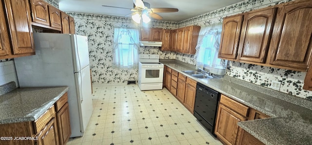 kitchen featuring under cabinet range hood, a sink, white appliances, wallpapered walls, and light floors