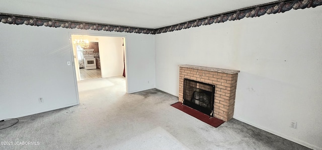 unfurnished living room with a chandelier, a brick fireplace, and baseboards