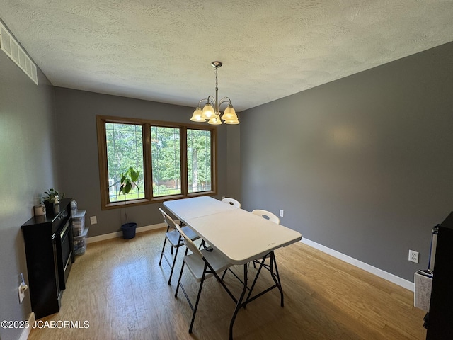 128 Don Dr, Linn, MO 65051 - dining room featuring light wood-style floors, a textured ceiling, and a chandelier