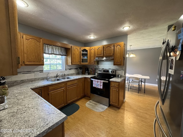 128 Don Dr, Linn, MO 65051 - kitchen featuring stainless steel electric range oven, freestanding refrigerator, under cabinet range hood, brown cabinetry, and light wood finished floors