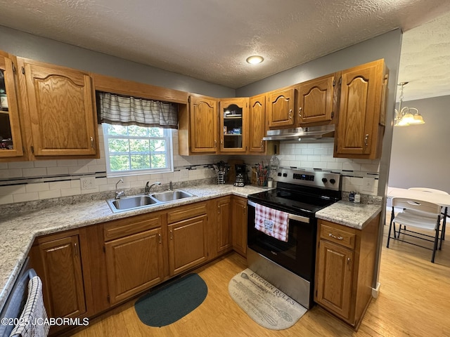 128 Don Dr, Linn, MO 65051 - kitchen with stainless steel range with electric stovetop, under cabinet range hood, light wood-type flooring, brown cabinetry, and a textured ceiling