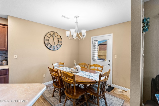 dining space featuring a chandelier, visible vents, baseboards, and light wood-style floors