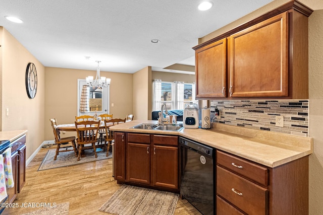 kitchen featuring a sink, tasteful backsplash, light wood-style floors, a peninsula, and dishwasher