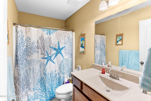 bathroom with vanity, curtained shower, toilet, and a textured wall