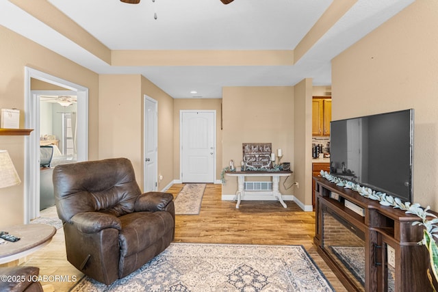 living room with visible vents, baseboards, light wood-type flooring, and ceiling fan