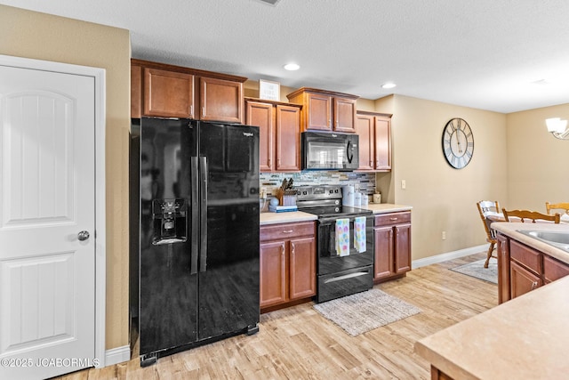 kitchen featuring light wood-style flooring, decorative backsplash, black appliances, light countertops, and brown cabinets