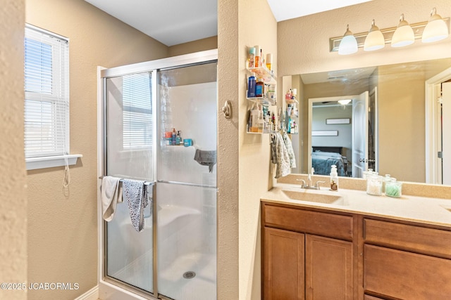 ensuite bathroom featuring connected bathroom, a stall shower, vanity, and a textured wall