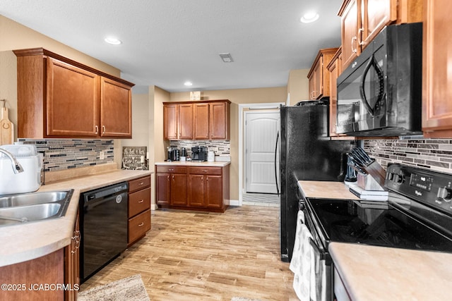 kitchen featuring black appliances, light wood-style flooring, light countertops, and brown cabinets