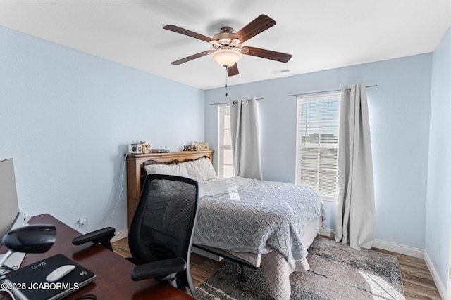 bedroom featuring visible vents, baseboards, wood finished floors, and a ceiling fan