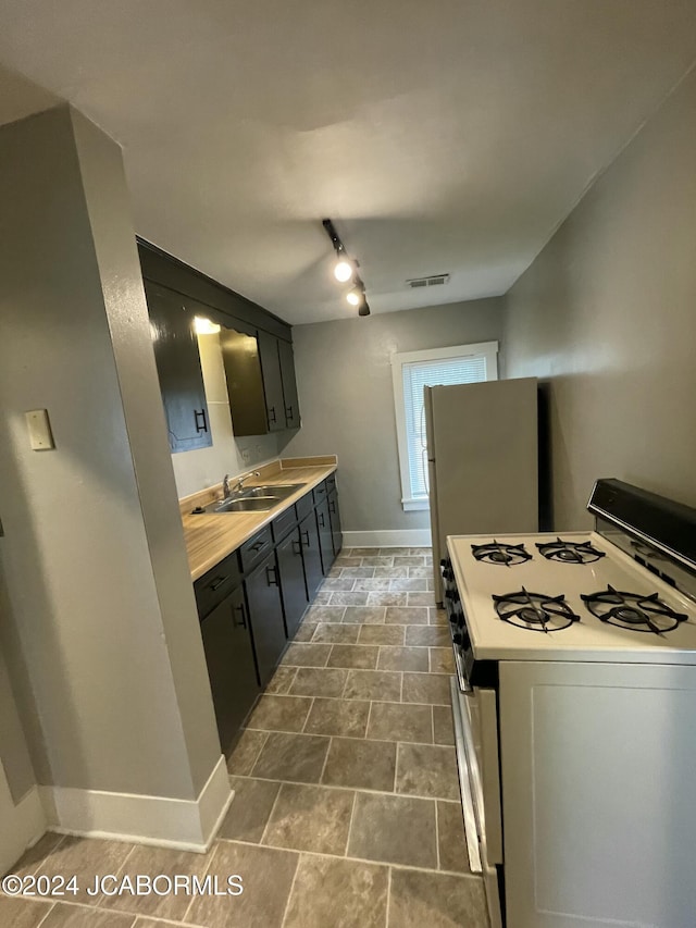 kitchen featuring rail lighting, white range with gas stovetop, and sink