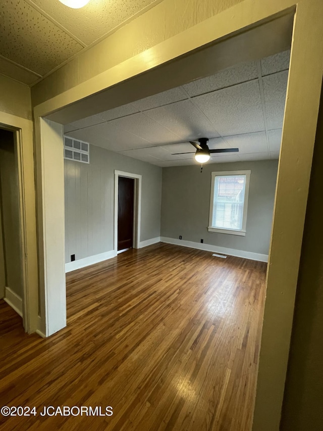 spare room with wood-type flooring, a drop ceiling, and ceiling fan