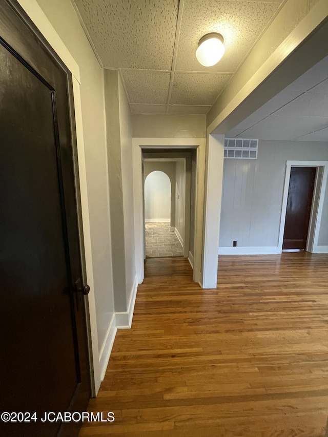 hall featuring hardwood / wood-style flooring and a drop ceiling