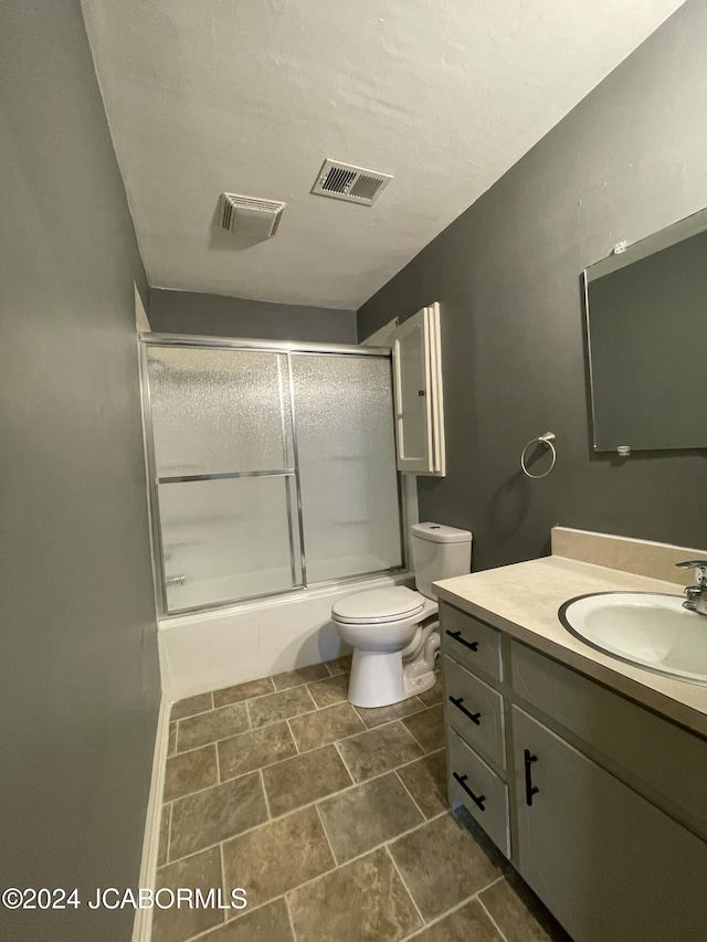 full bathroom featuring vanity, toilet, and bath / shower combo with glass door