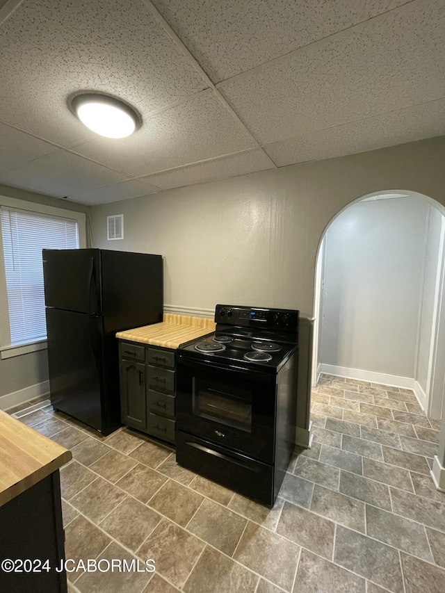 kitchen with black appliances, a paneled ceiling, and wood counters