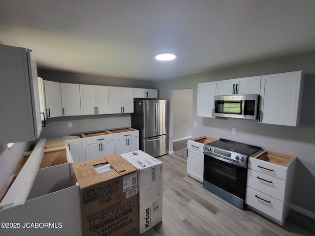 kitchen with baseboards, white cabinets, appliances with stainless steel finishes, and light wood finished floors