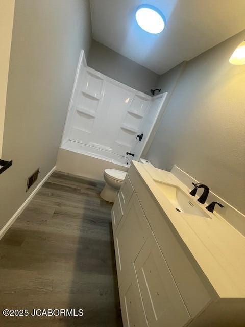 bathroom with shower / washtub combination, wood finished floors, visible vents, toilet, and vanity