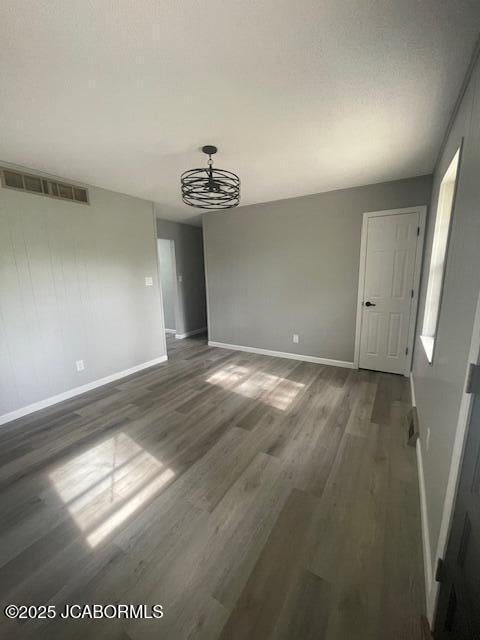 unfurnished dining area with wood finished floors, visible vents, and baseboards