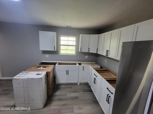 kitchen with light wood-style floors, white cabinets, and freestanding refrigerator