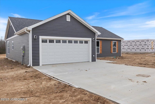 view of front facade featuring an attached garage, a shingled roof, and driveway