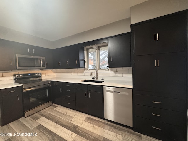 kitchen featuring sink, decorative backsplash, stainless steel appliances, and light wood-type flooring