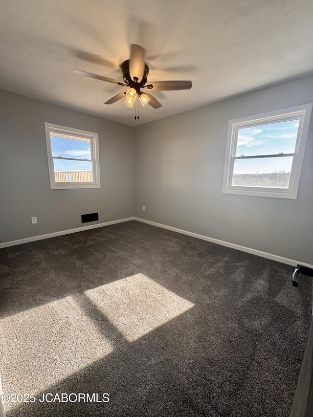 empty room with ceiling fan and dark carpet