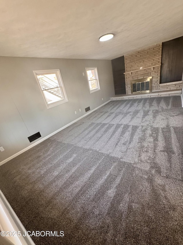 unfurnished living room with a large fireplace and carpet