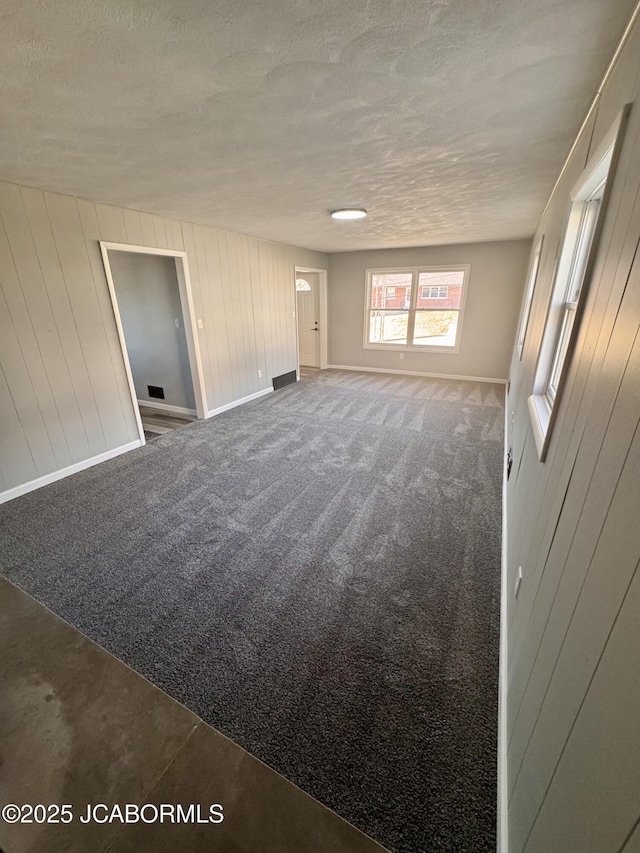 empty room with dark carpet and a textured ceiling