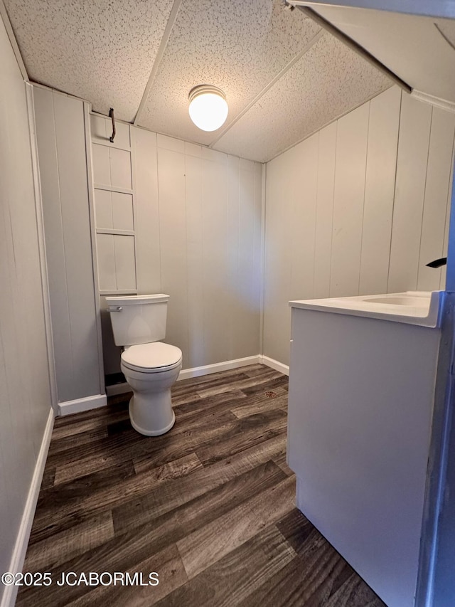 bathroom with a drop ceiling, hardwood / wood-style flooring, and toilet